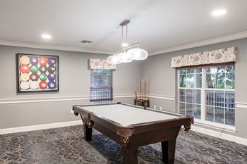 A pool table in a room with a painting of pool balls on the wall.